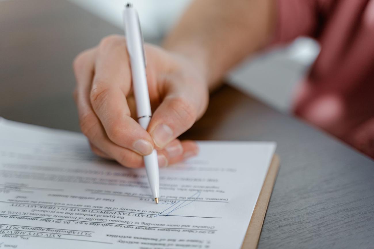 Mão assinando um documento com caneta