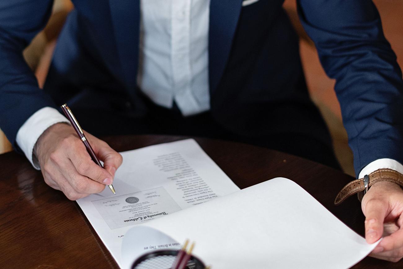 Pessoa assinando documentos sobre uma mesa
